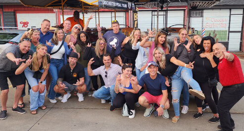 large group of people posing for a picture in front of a pedal pub bike