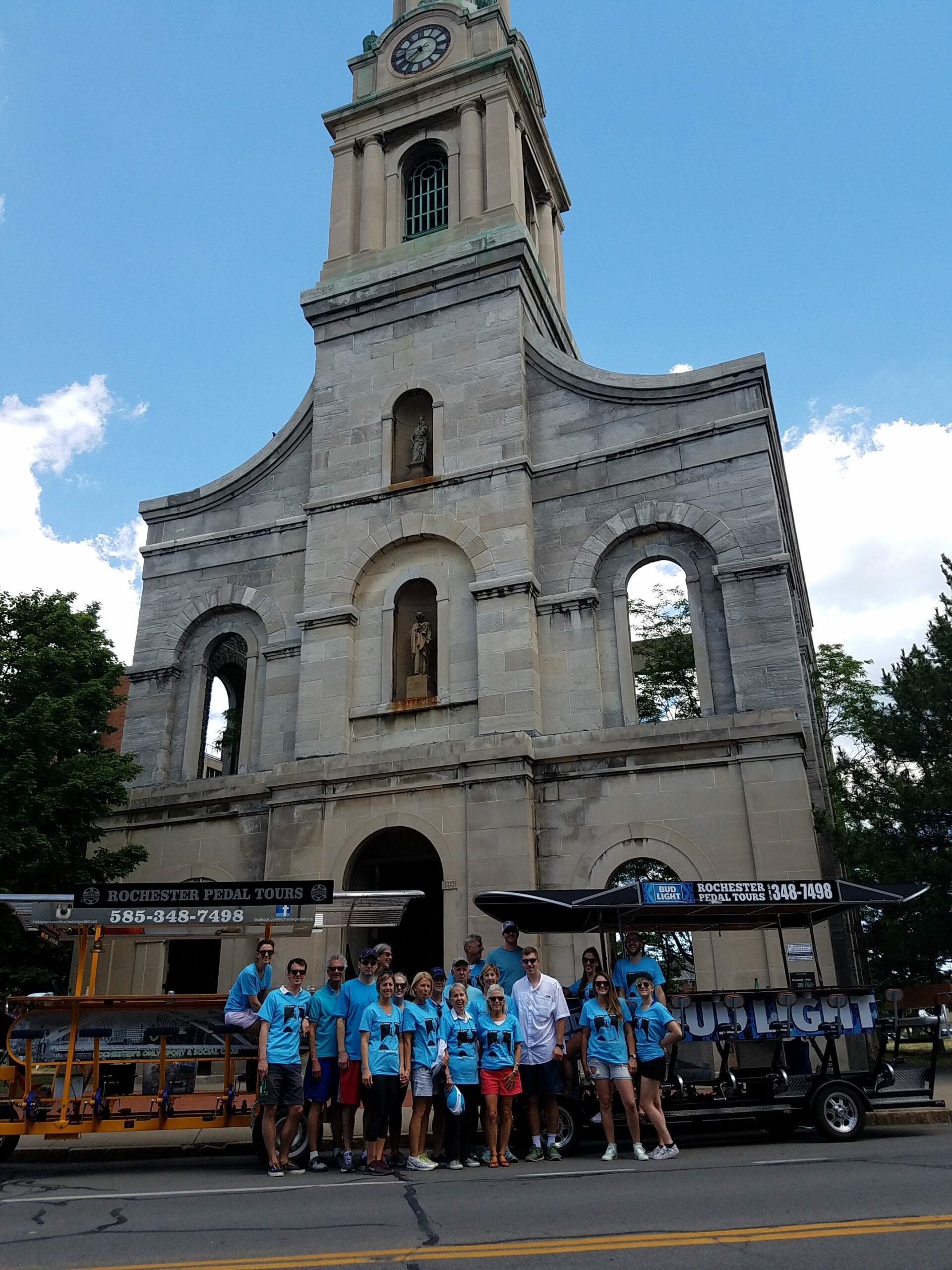 two pedal pubs and a group of people posing in front of a Cathedral of St Joseph