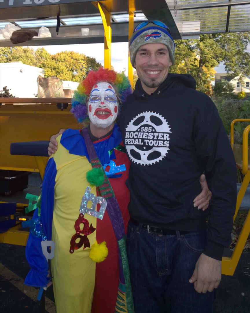 a guy with a hat on hugging a guy dressed as a clown in front of a orange pedal pub
