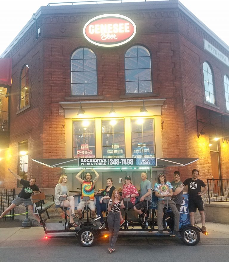 group of friends having fun on a pedal pub doing funny poses for a picture while doing a pedal tour