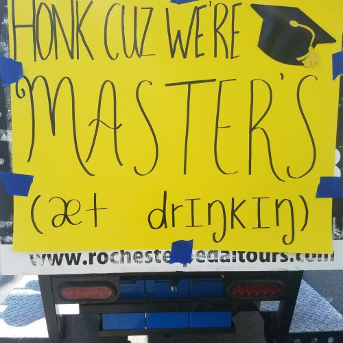 happy graduation sign on the back of a pedal pub