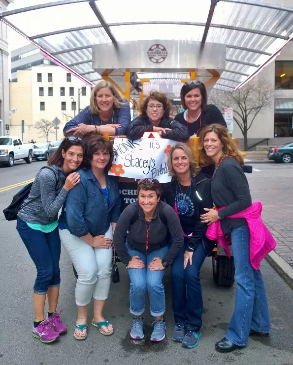 8 ladies posing in front of a pedal pub celebrating a birthday