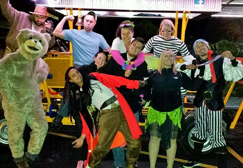 people masked for a haloween in costumes posing for a picture in front of a pedal pub