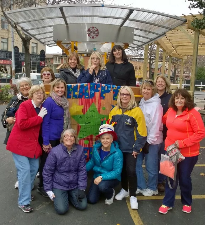 group of older ladies celebrating a birthday posing in front of a pedal pub